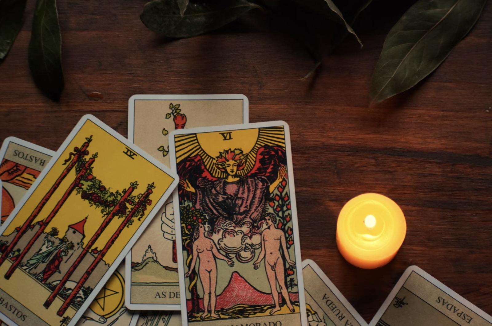 Rider-Waite tarot cards spread across a wooden table beside a notebook and pen.