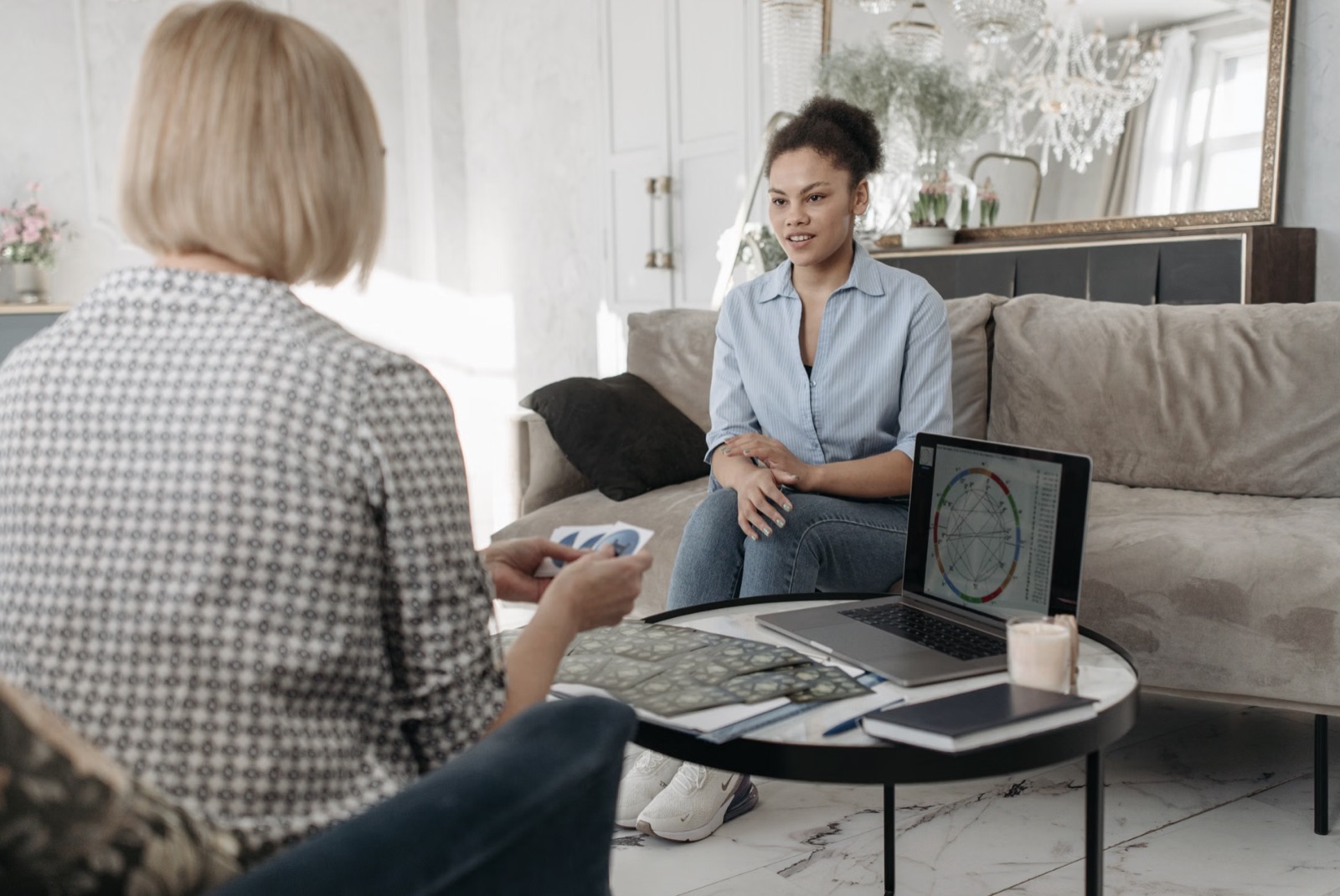 A person uses a laptop for an AI tarot reading while tarot cards rest beside the keyboard.
