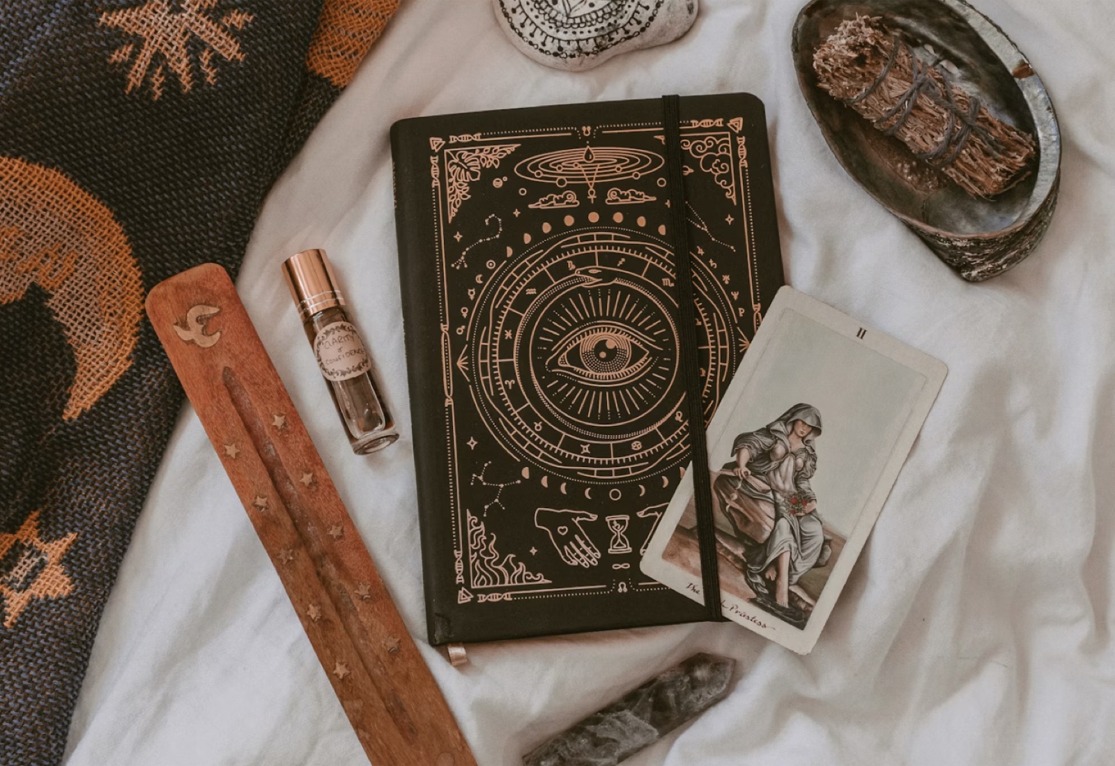 A flat lay of a tarot ritual table with cards, candles, tea, and a notebook prepared for a reading.