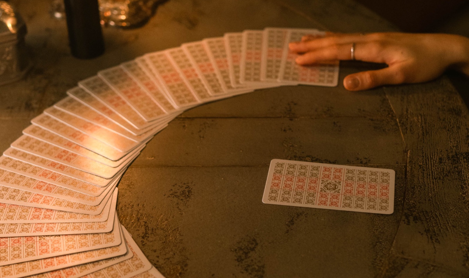 A realistic tarot reading setup with hands near cards on a table.