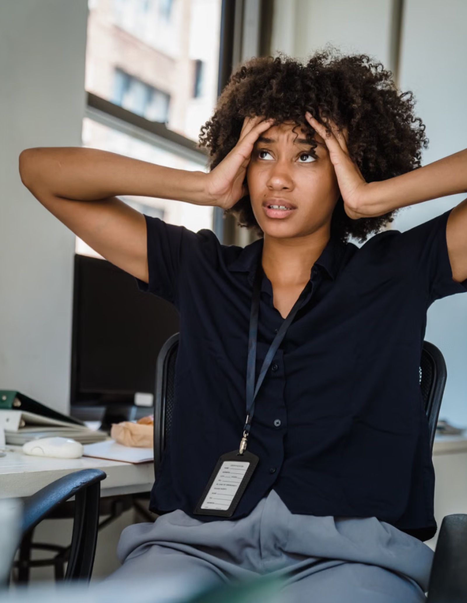 A stressed professional sitting at a desk in an office.