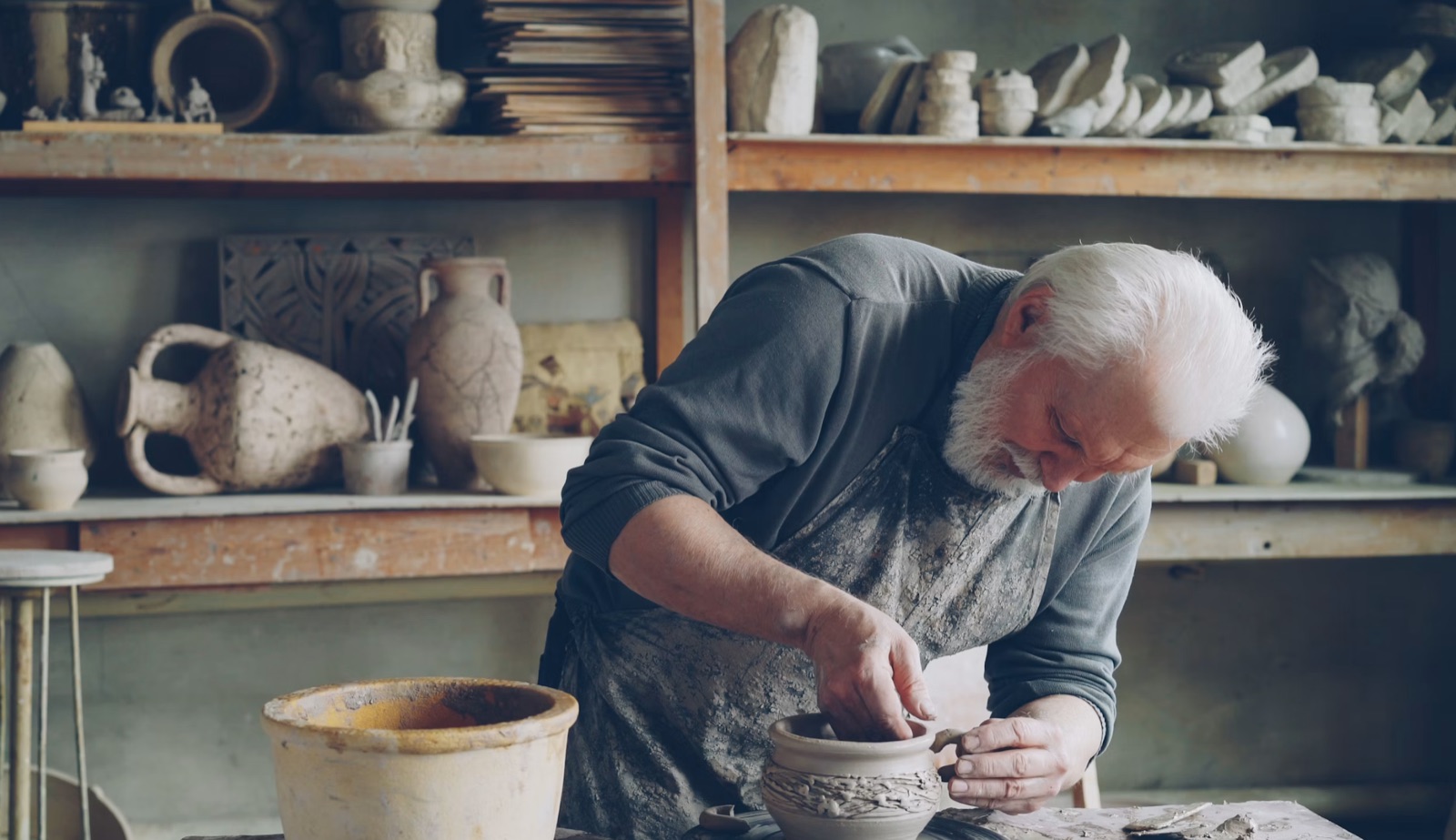 A craftsperson working carefully with clay in a pottery studio.