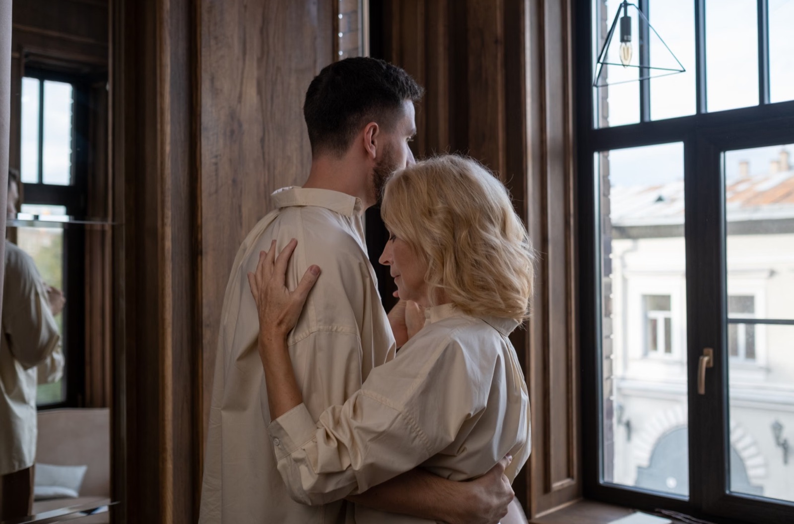 A couple in soft window light, representing emotional safety, closeness, and a calm sense of home.
