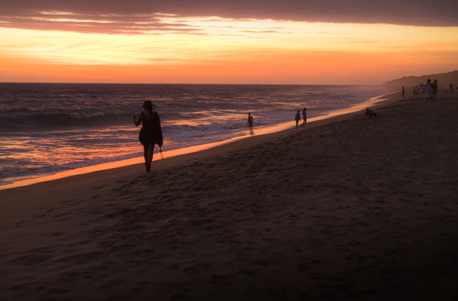 A person walking alone on a beach at sunset
