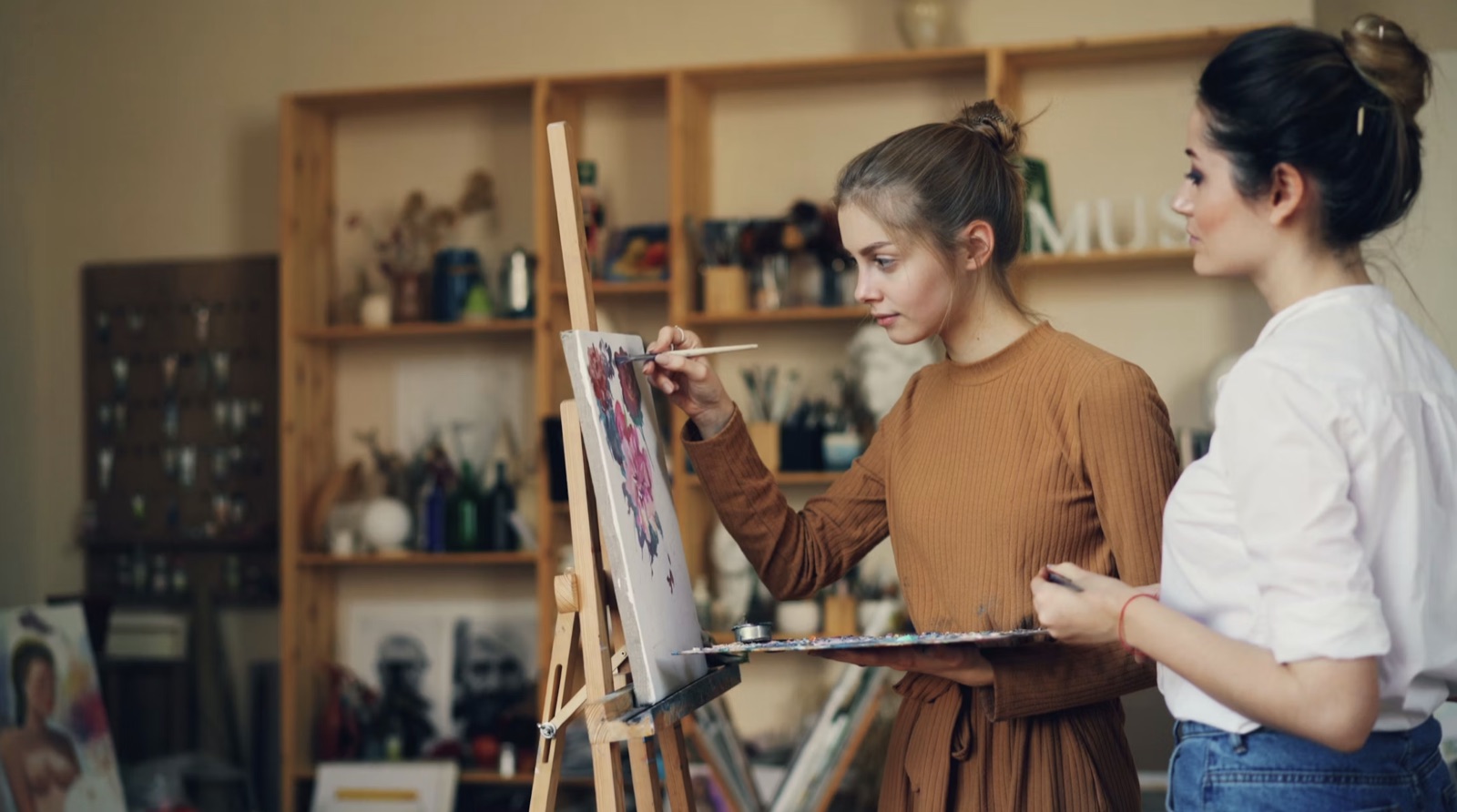 Two women collaborating in a creative studio, reflecting the shared momentum and collaborative success of the Three of Cups.