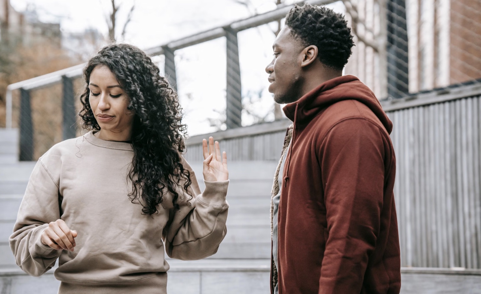 A couple in visible conflict outdoors, reflecting criticism, emotional distance, and unstable communication.
