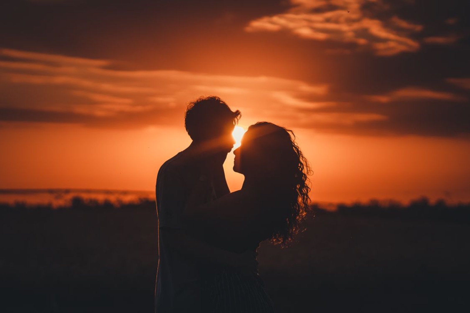 A couple standing together at sunset near the water, suggesting a relationship at a turning point.