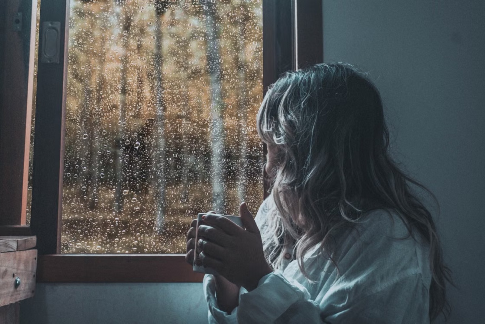 A person alone by a window, quiet and reflective, suggesting emotional self-protection.