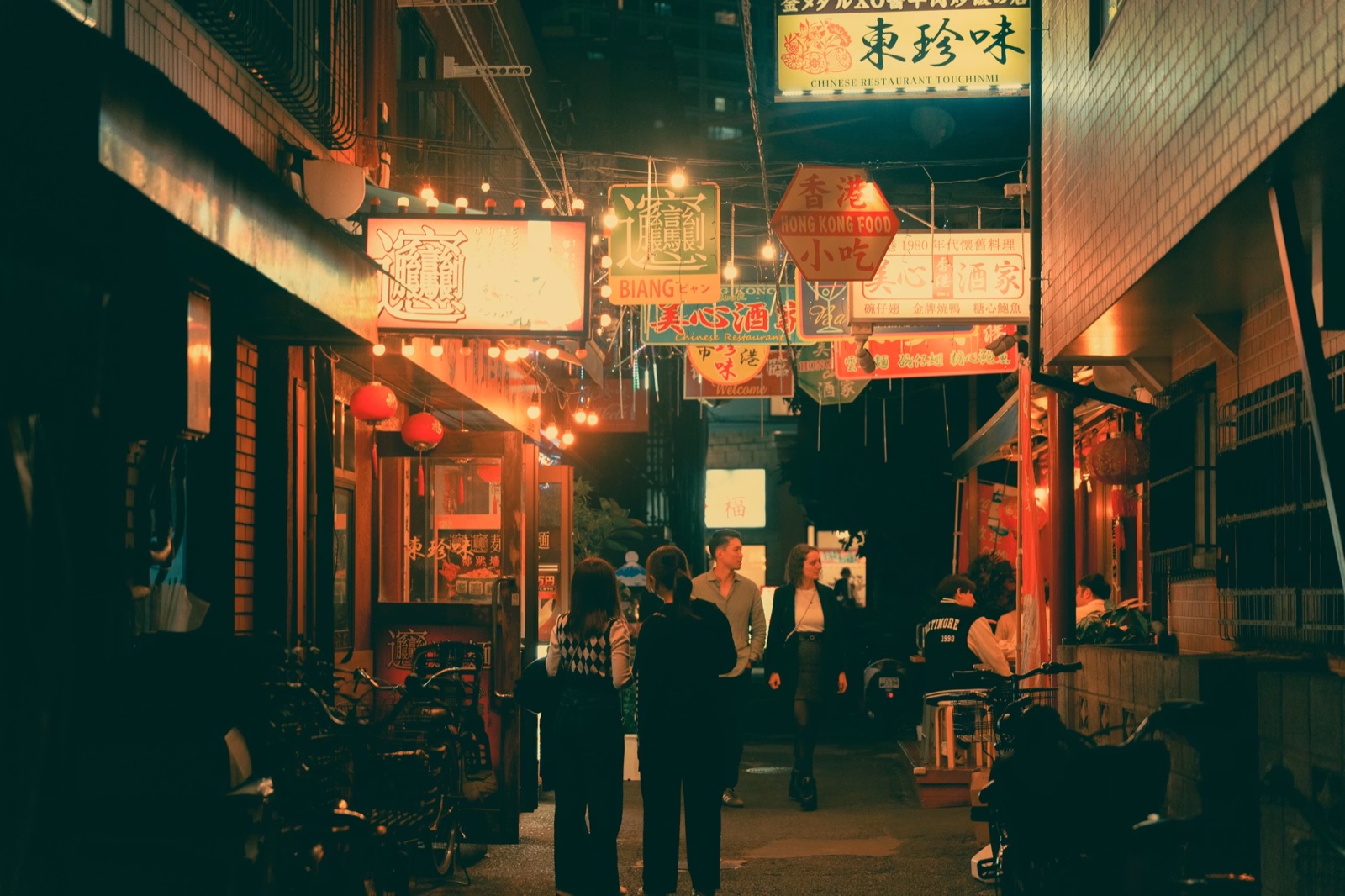 A woman alone at night in the city, looking at her phone while waiting, capturing the uncertainty of mixed signals and no contact.