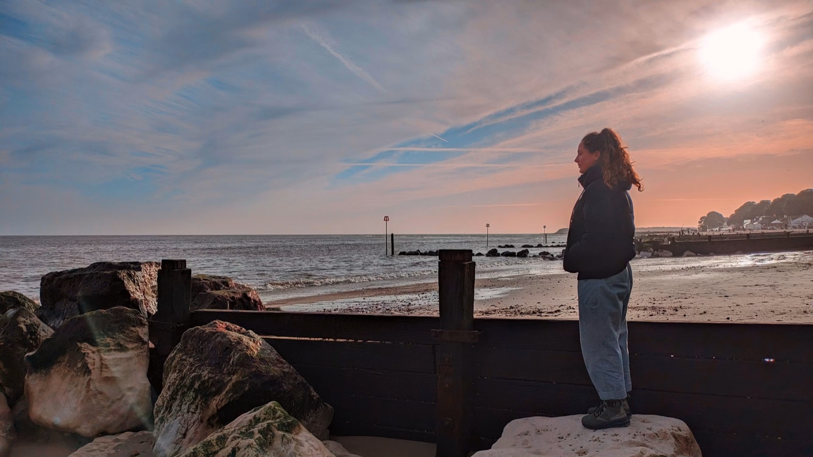 A woman alone by the sea in a reflective moment, representing clarity, grounded self-trust, and emotional perspective.