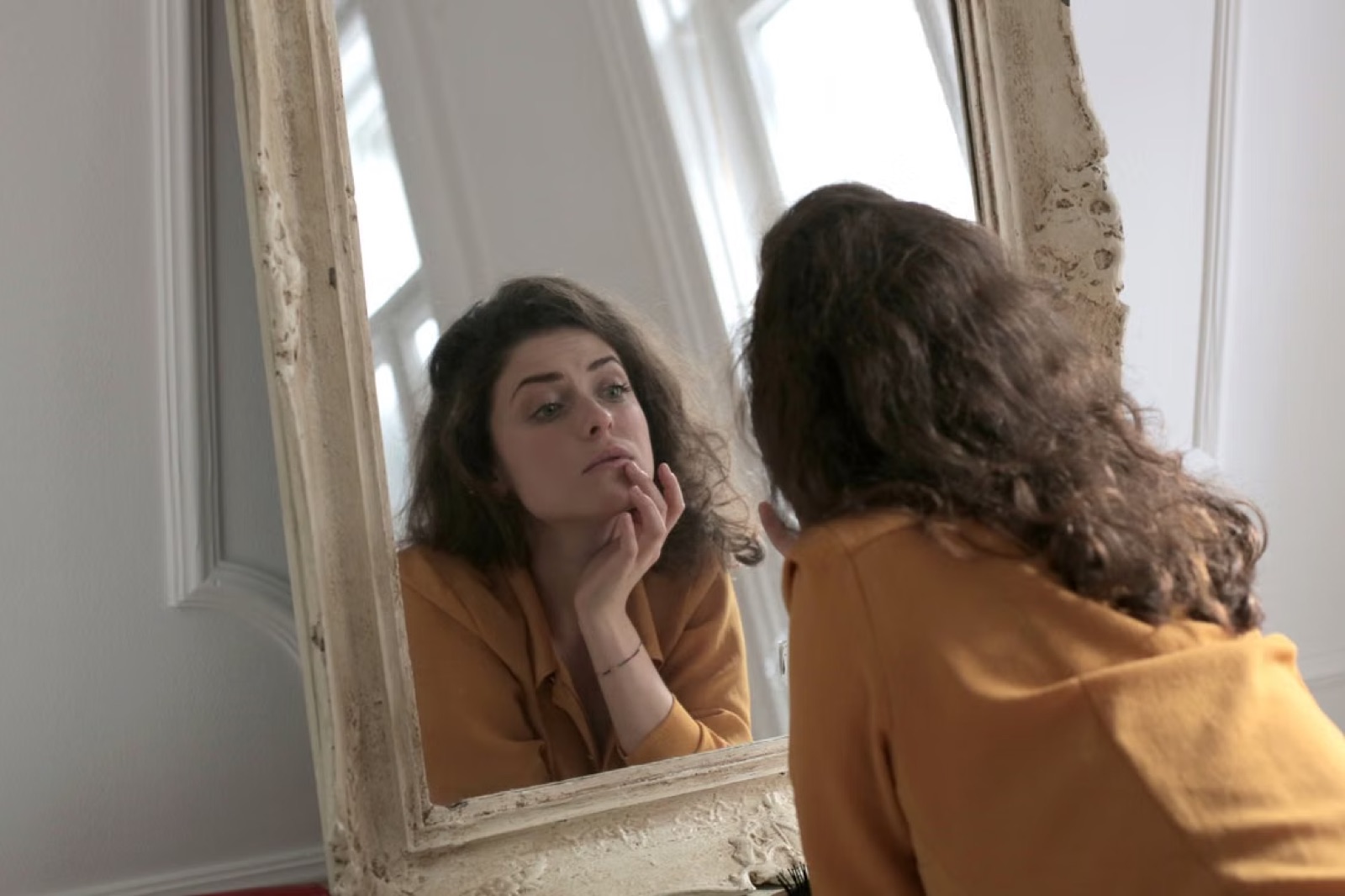 A person looking into a mirror, reflecting the Seven of Cups theme of projection, emotional uncertainty, and the search for clarity in love.