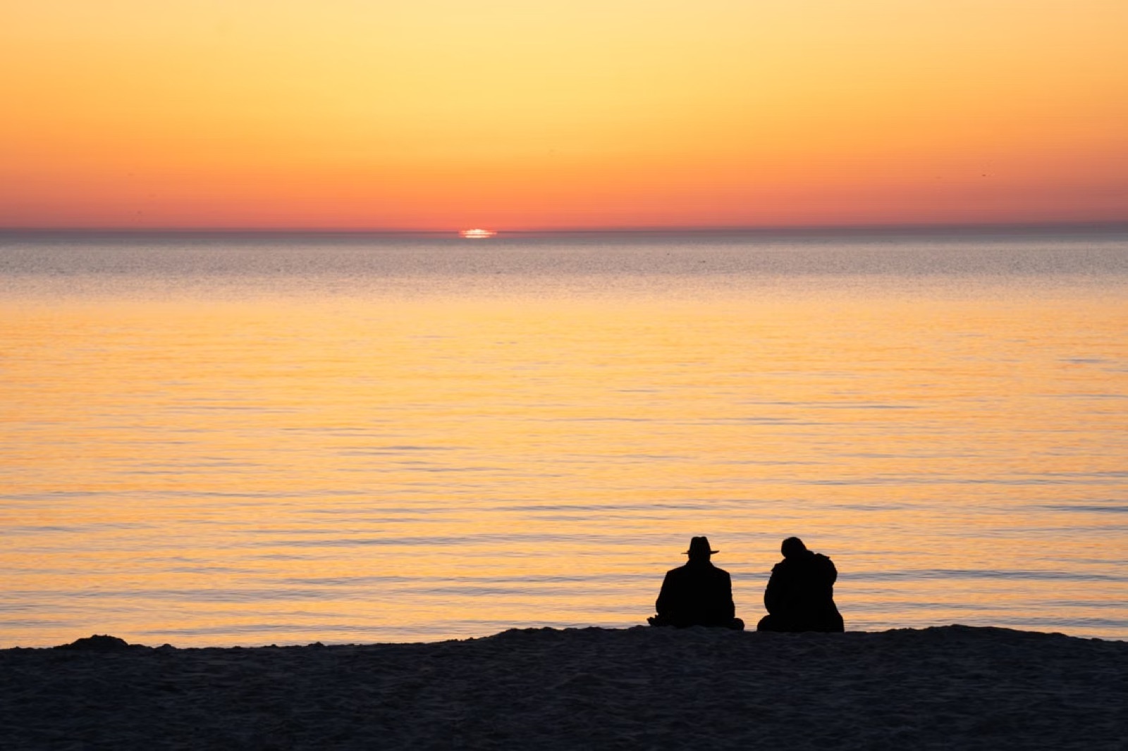 Two people near the seaside with emotional distance between them, expressing unresolved feelings and the uncertain possibility of reconciliation.