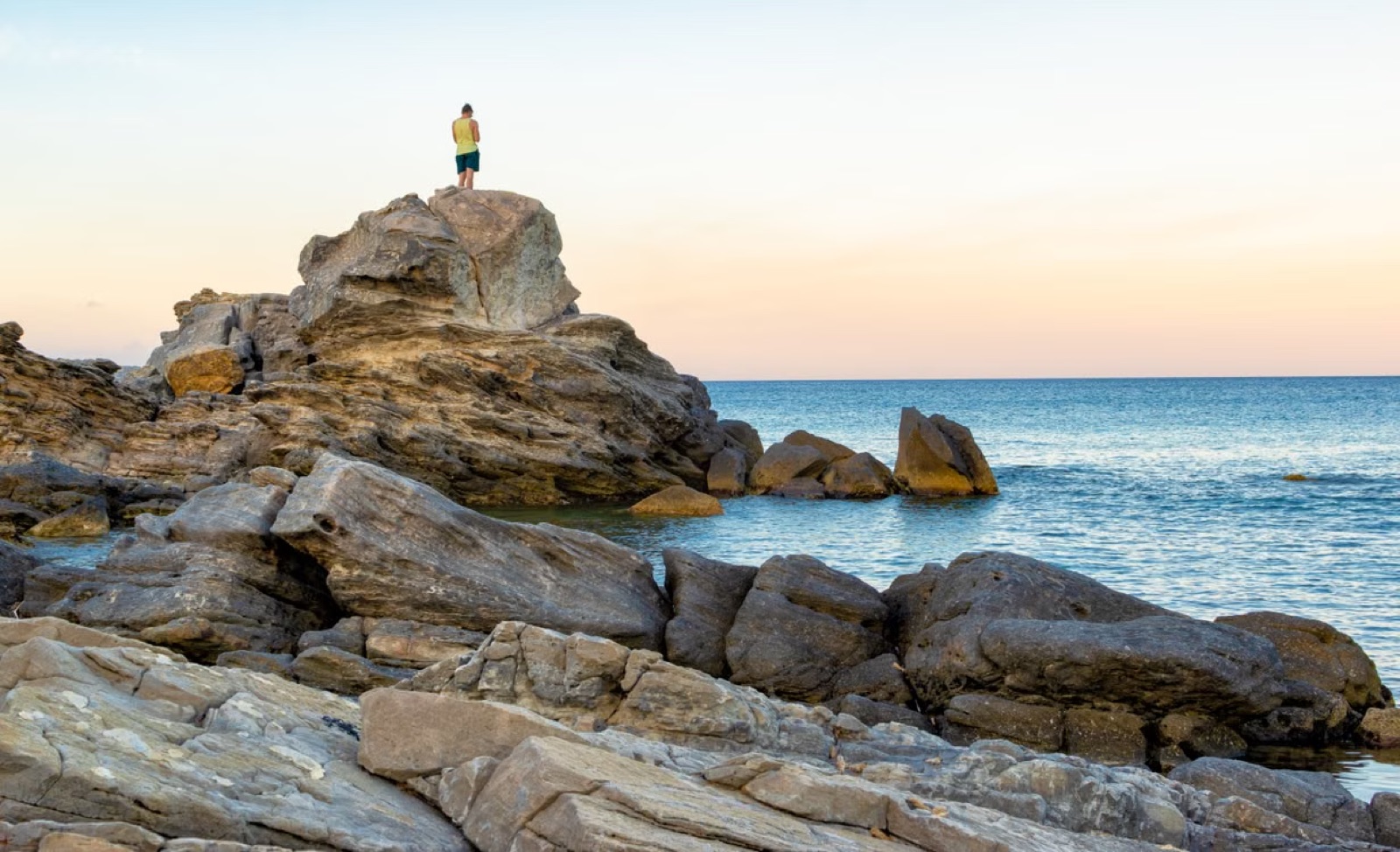 A person standing at sunrise on a cliff, suggesting recovery, perspective, and the beginning of emotional rebuilding.