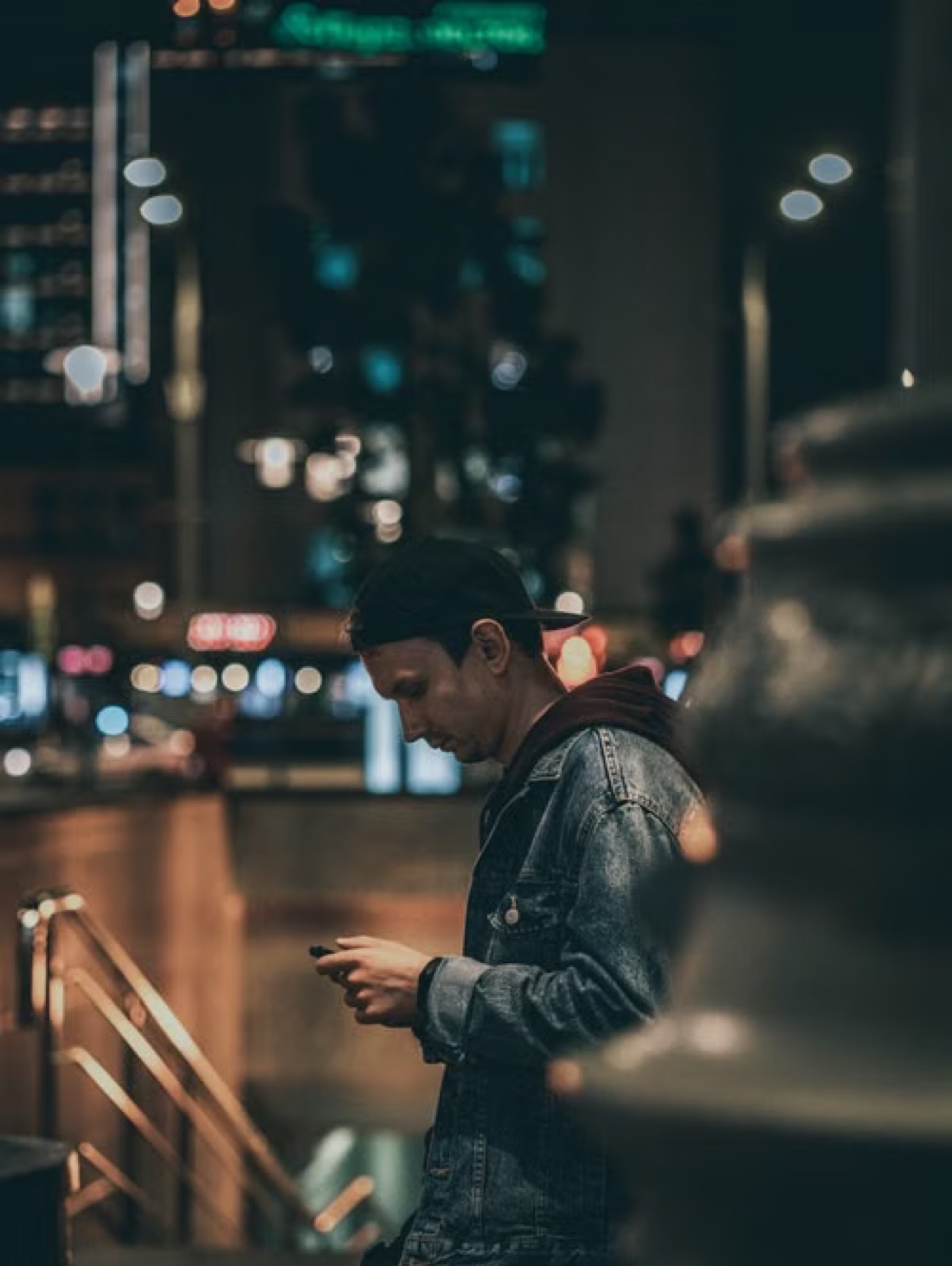 A person alone at night looking at a phone by the window, suggesting silence, unresolved thought, and the urge to send a message.