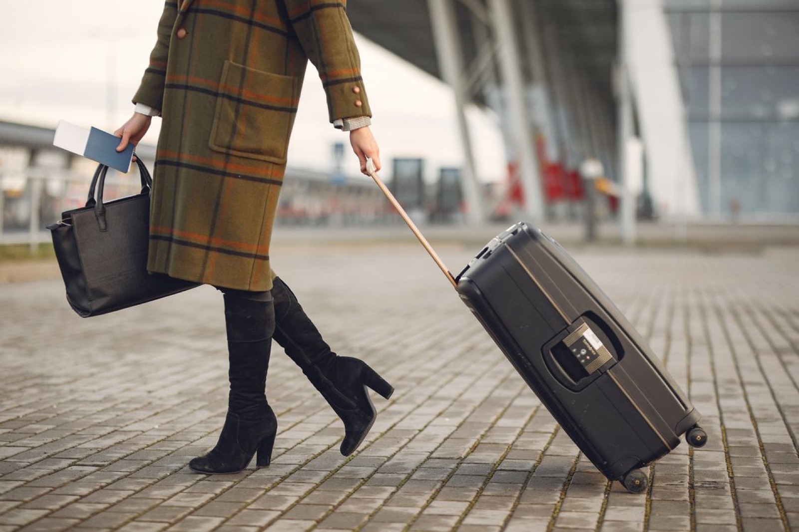 A traveler walking with luggage outside a modern airport, symbolizing departure, transition, and career change.