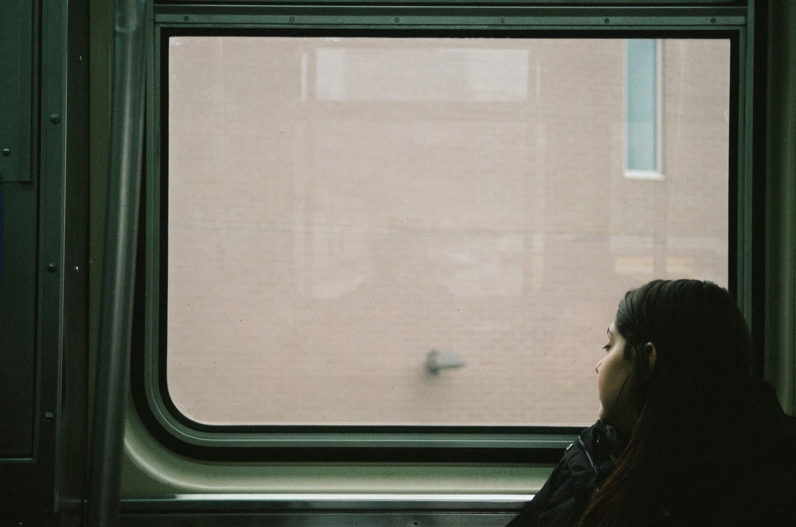 A woman sitting on a train looking out the window during a quiet journey.