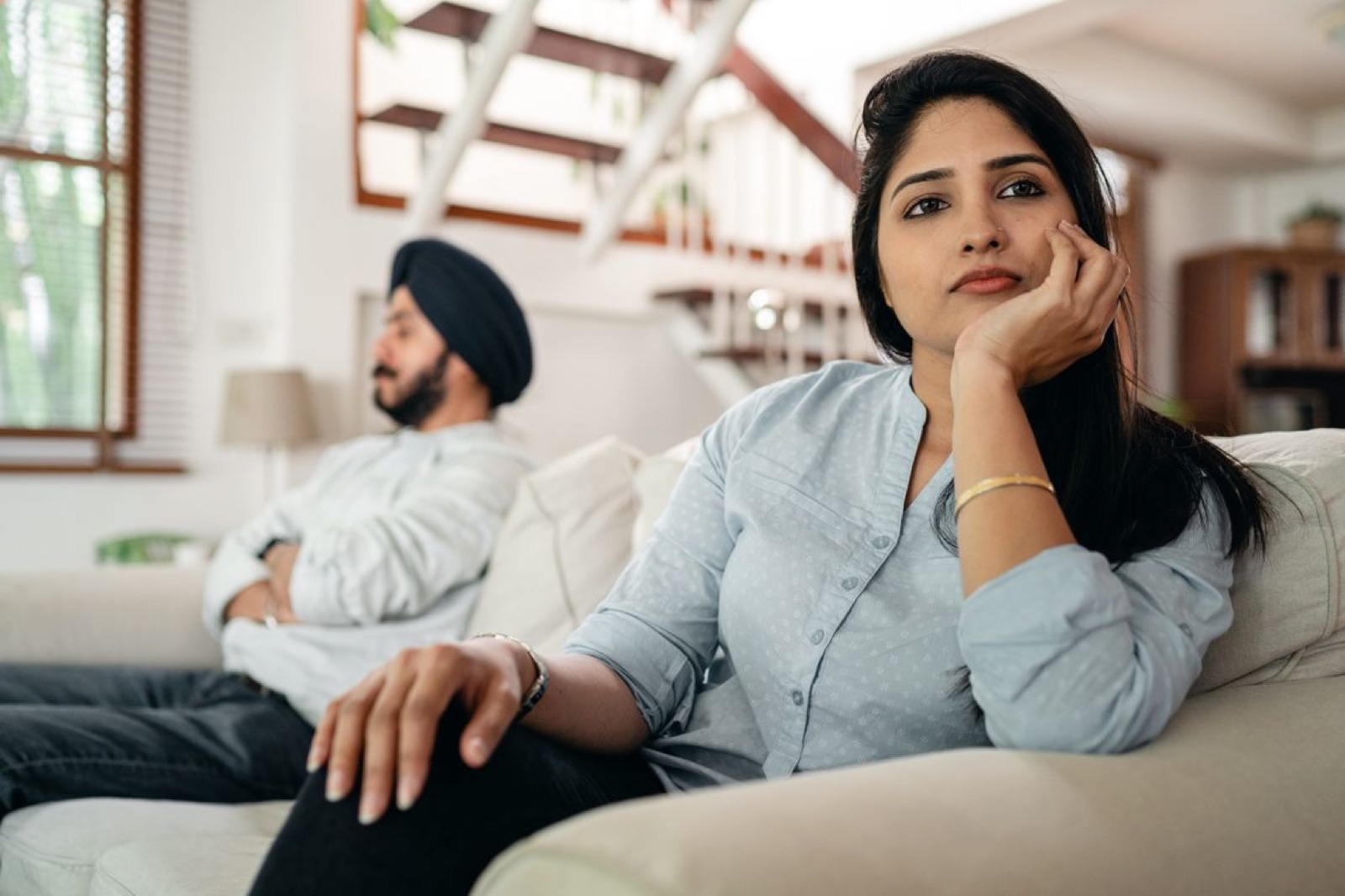 A couple sitting apart in a quiet, tense moment, representing emotional stagnation in love.