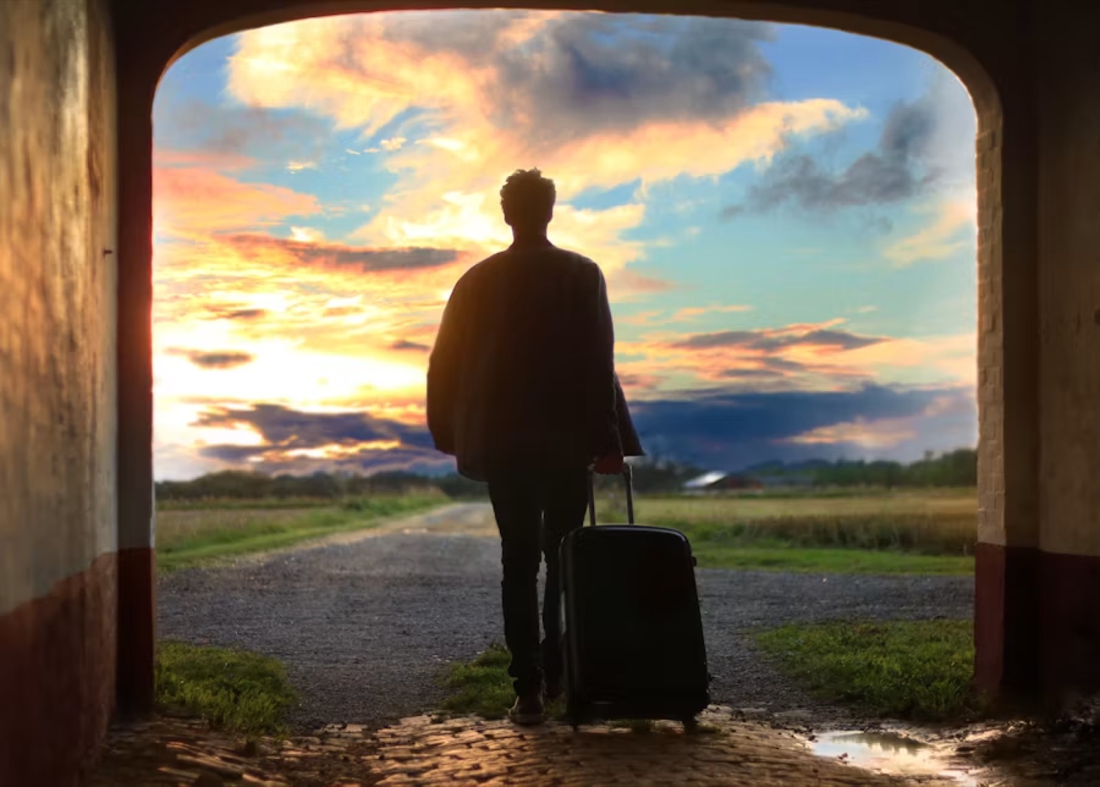 A person walking toward a new road, station, or city street at dawn or dusk, carrying the feeling of leaving an old phase and stepping into a new direction.