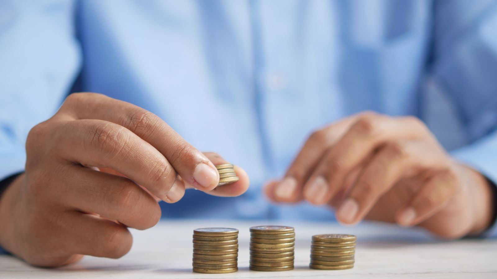 A hand tightly clutching gold coins, conveying a defensive, gripping energy.