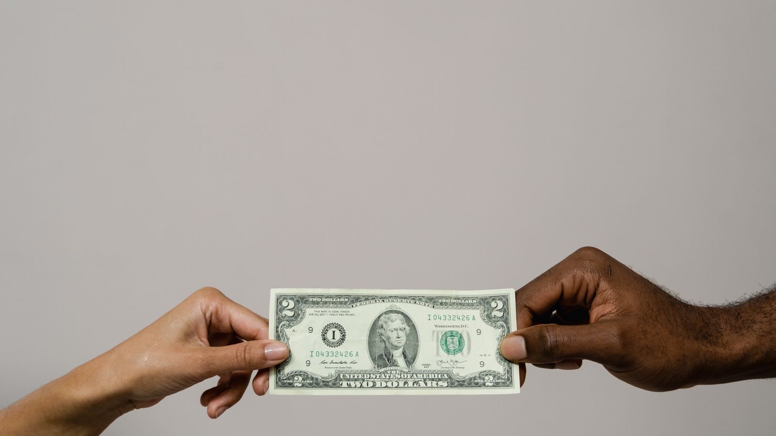 A hand giving a coin to another outstretched hand, warm light, conveying generosity and fair exchange.