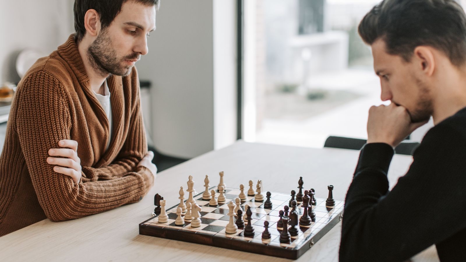 Two people focused over a chess board, capturing the analytical clarity of the King of Swords.